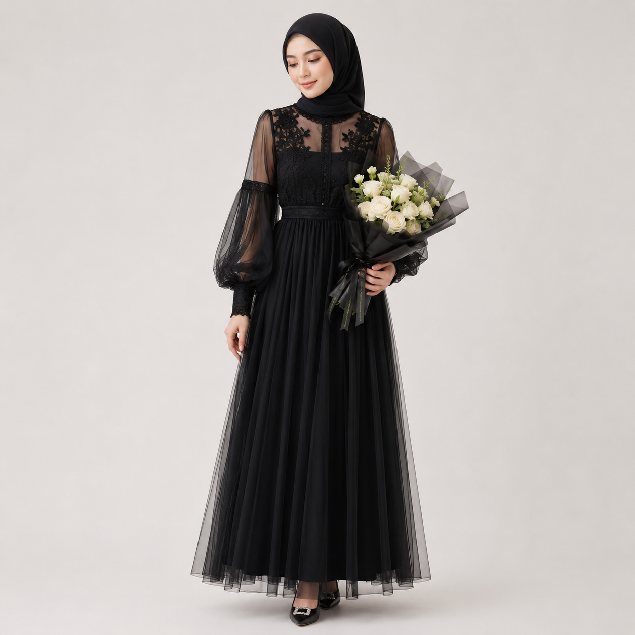 Woman wearing a black dress with sheer sleeves holding flowers on a white background