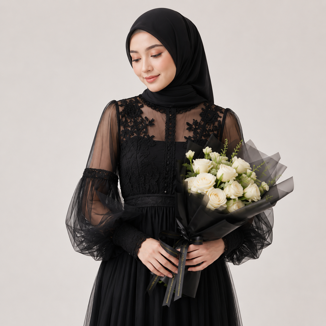 Woman in a black dress with sheer sleeves holding a bouquet of white roses against a plain background