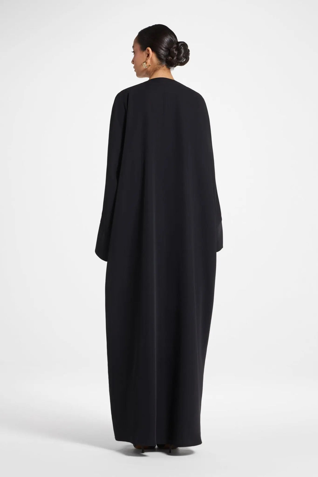 Woman wearing a black abaya on a white background