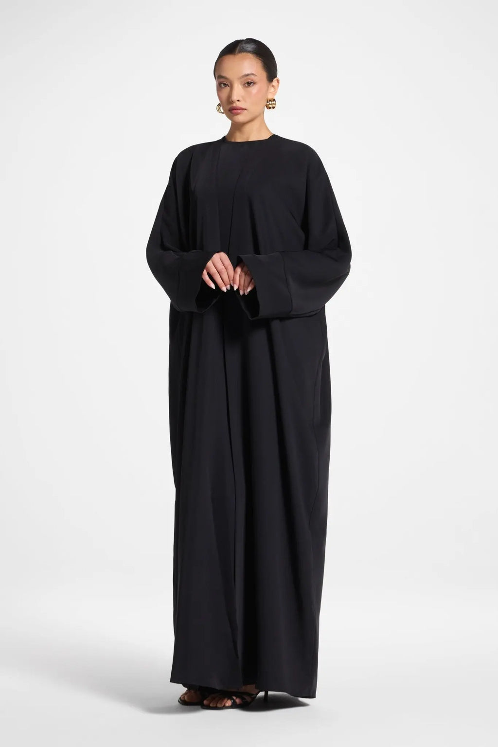 Woman wearing a black long-sleeve dress on a white background