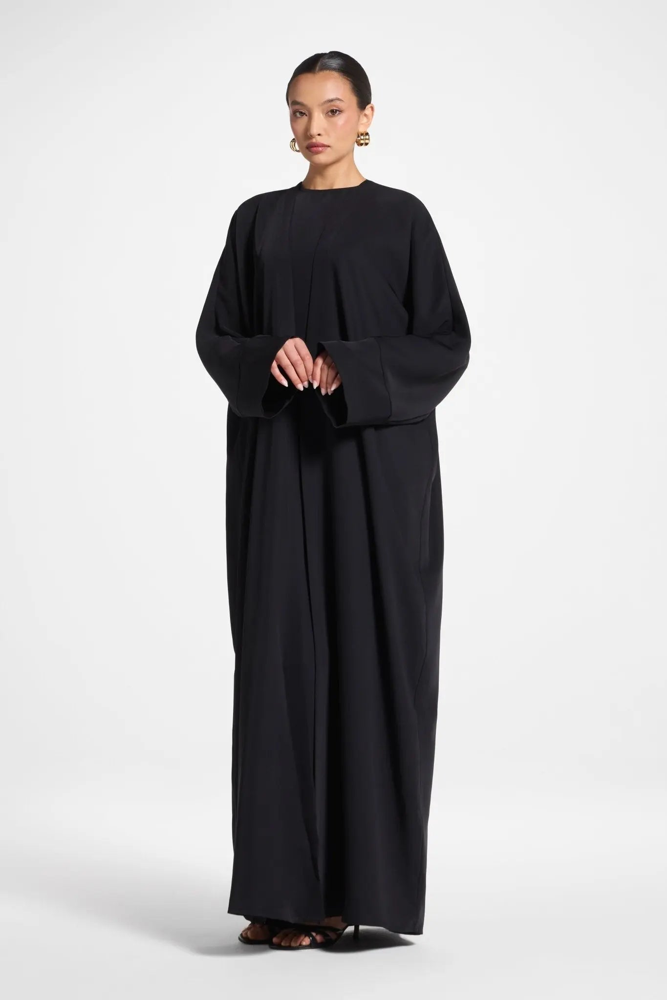 Woman wearing a black long-sleeve dress on a white background