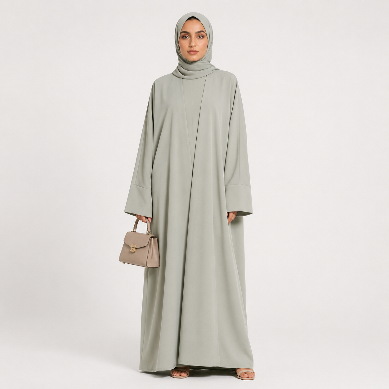 Woman wearing a light gray abaya with a matching hijab on a white background
