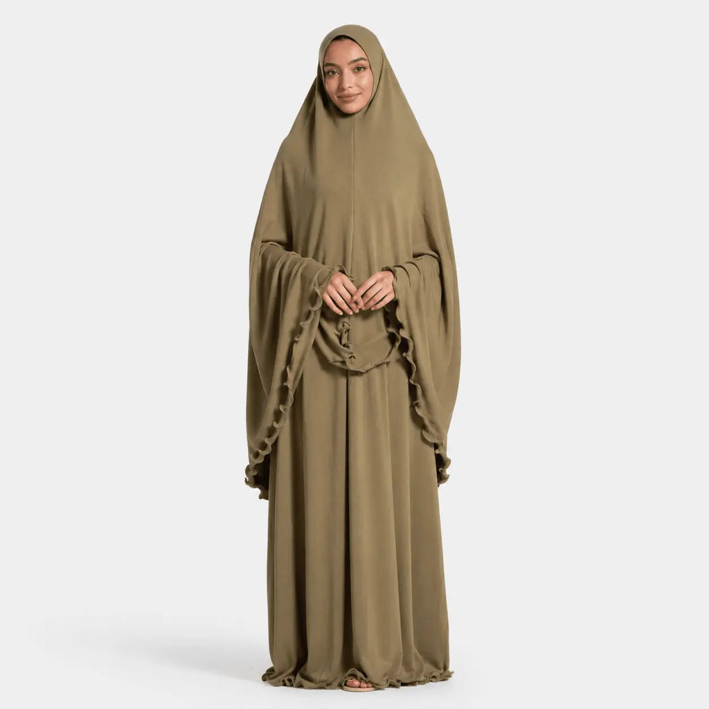 Woman wearing a long, light brown abaya on a white background