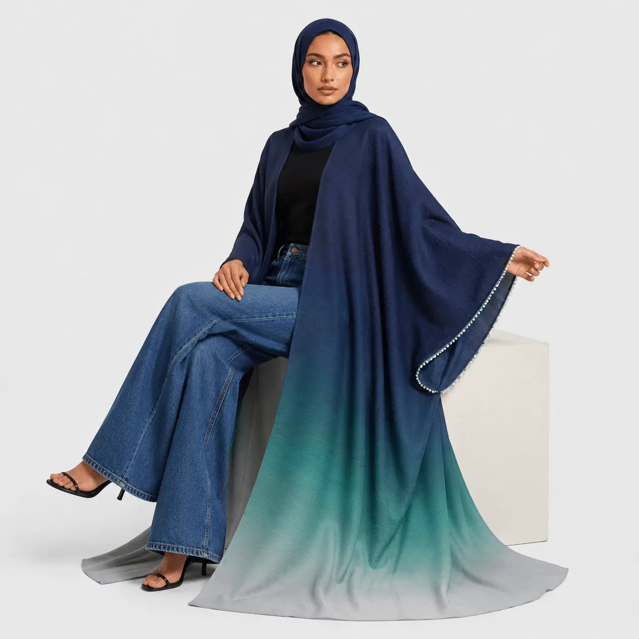 Woman wearing a blue and green gradient hijab with denim pants on a white background