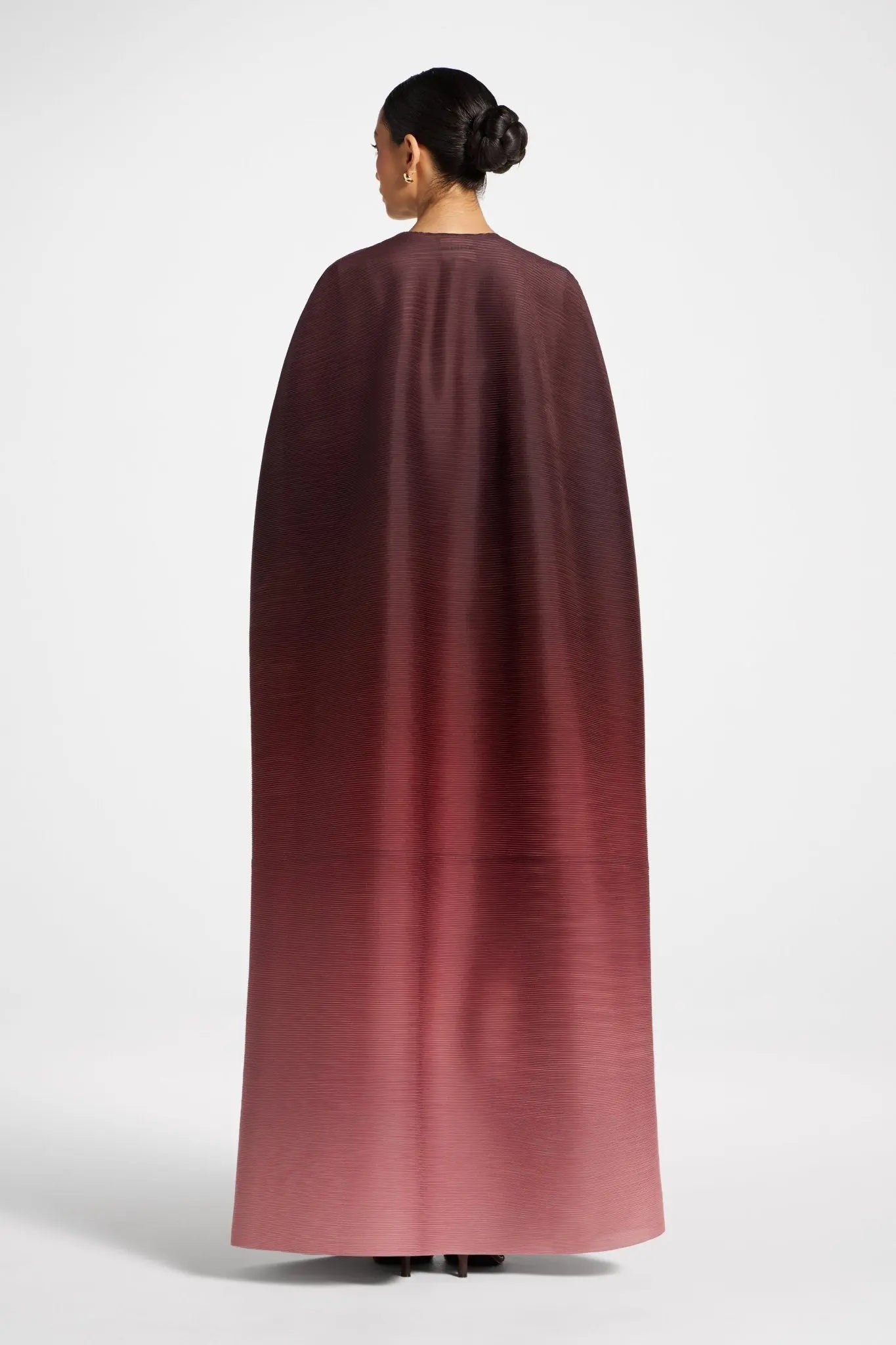 Person wearing a long burgundy cape on a white background