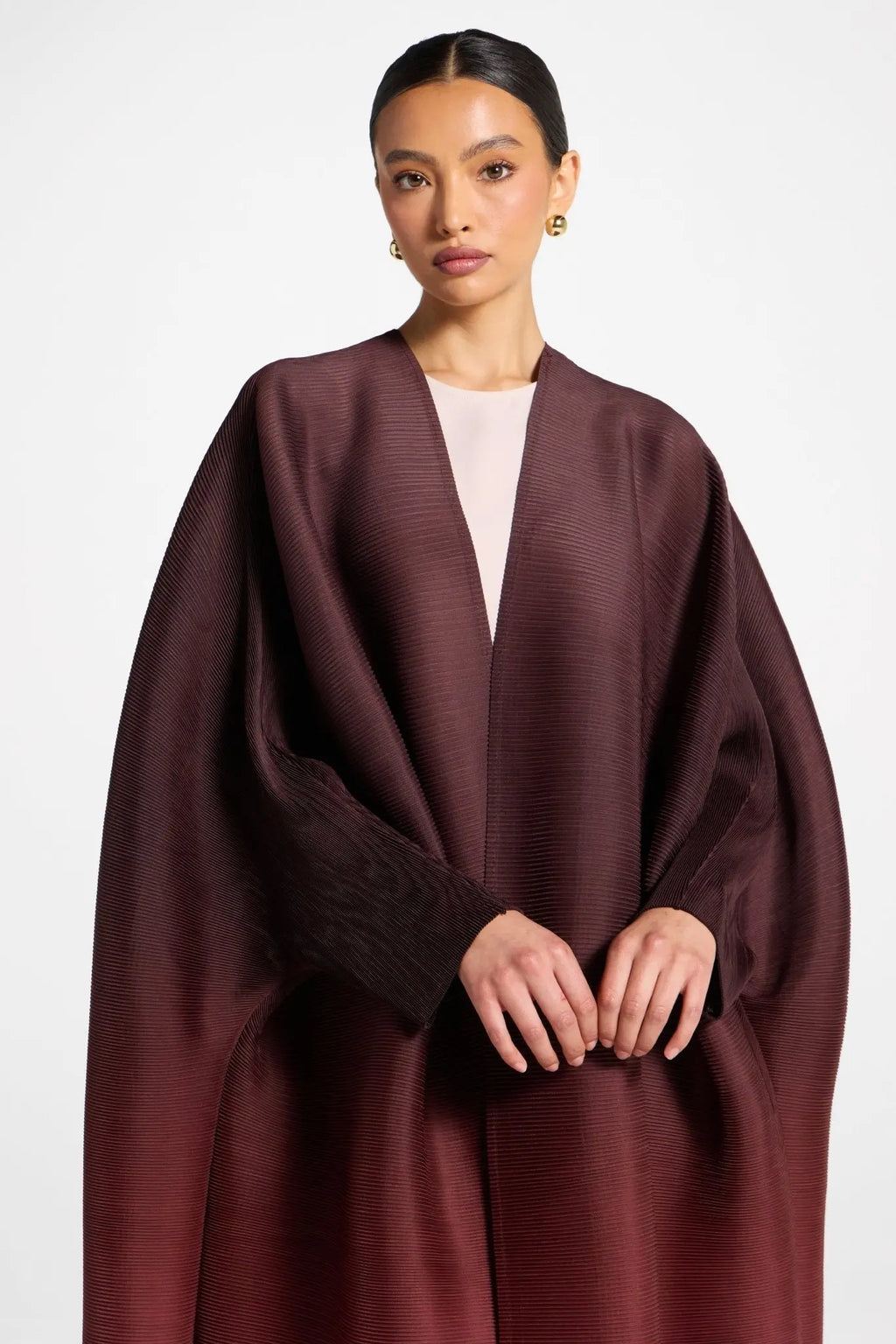 Woman wearing a burgundy cape over a plain background