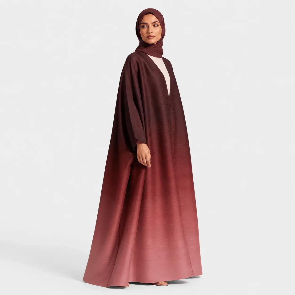 Woman wearing a long, dark red abaya on a white background