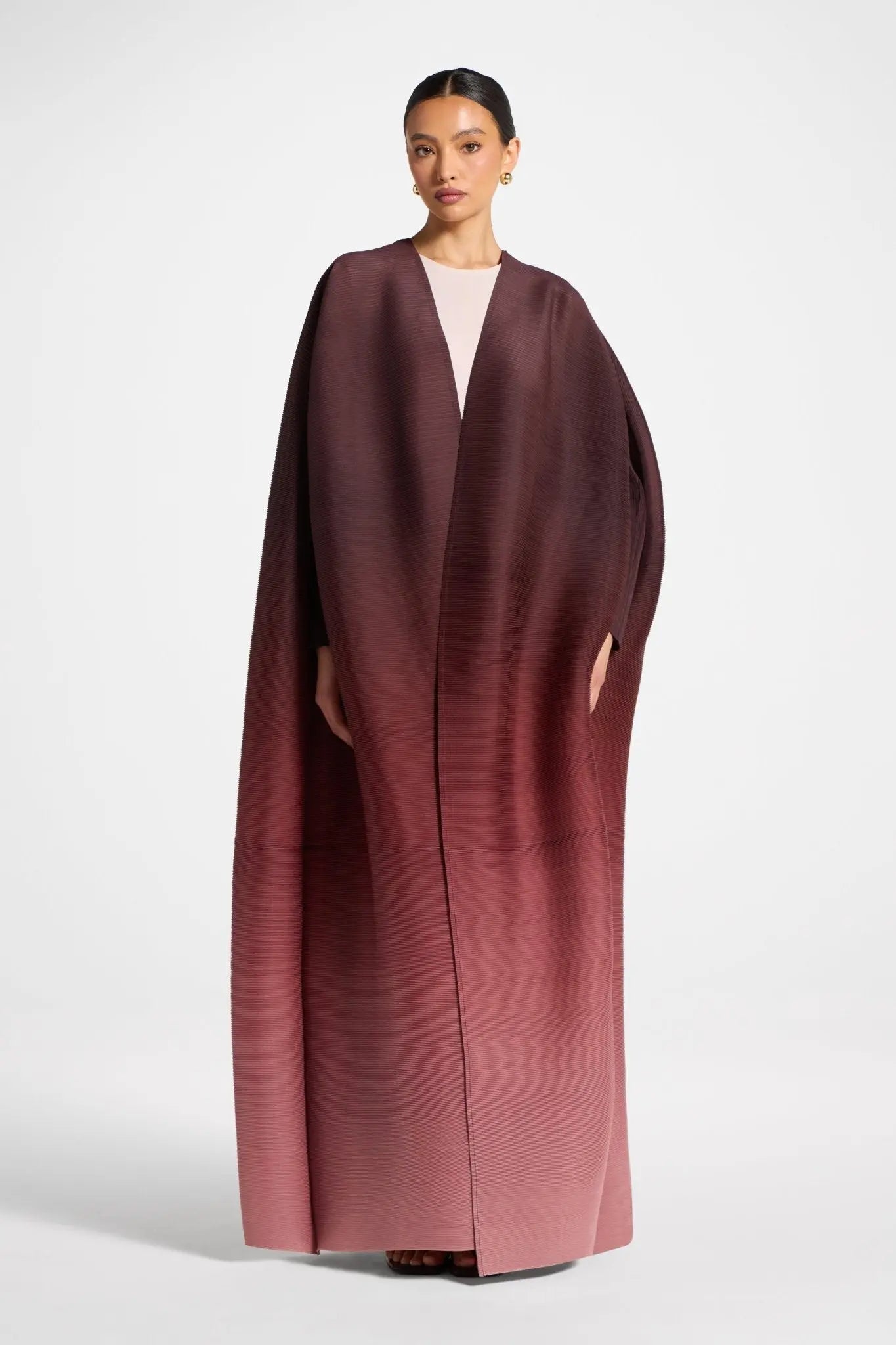 Woman wearing a long burgundy coat on a white background