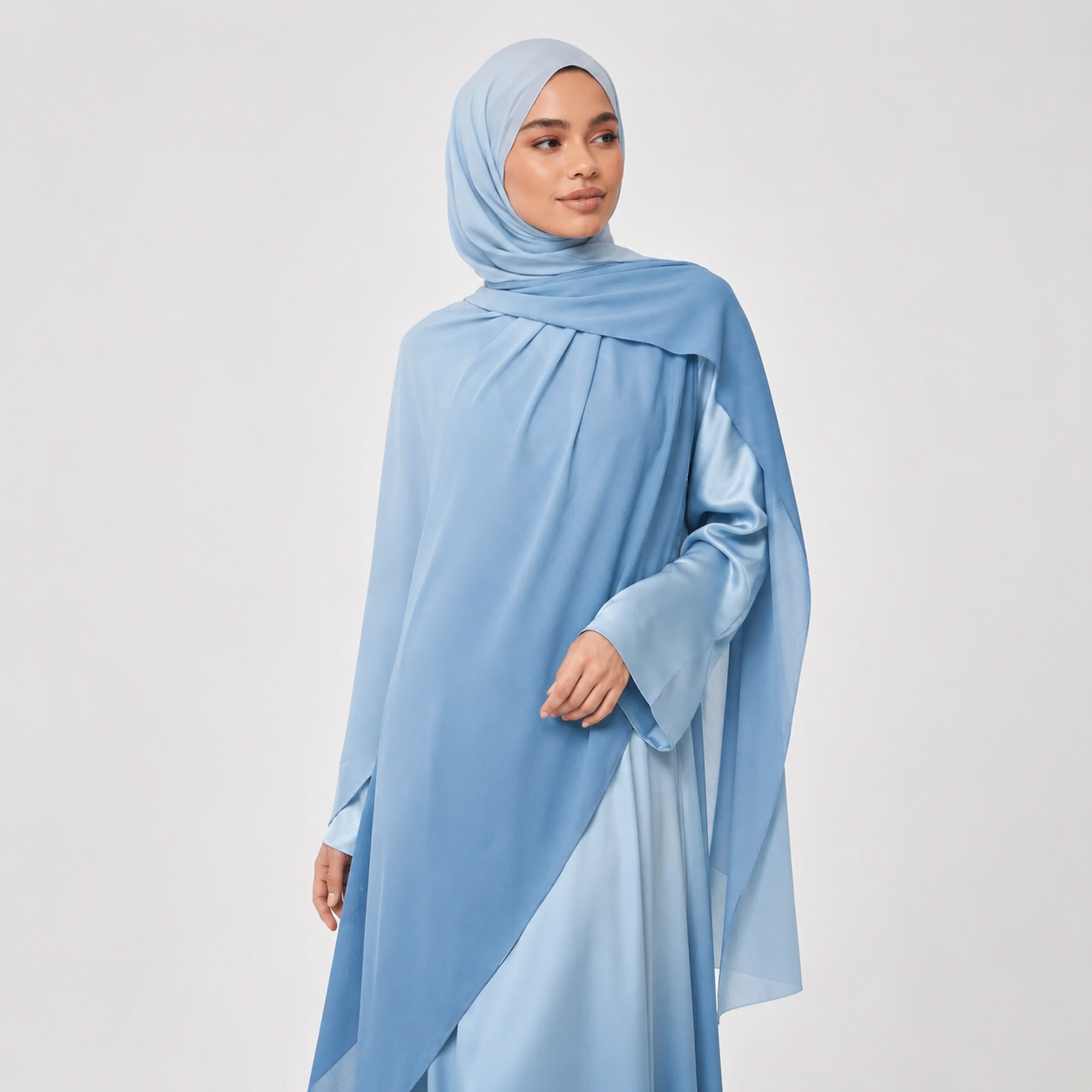 Woman wearing a light blue hijab and dress against a white background