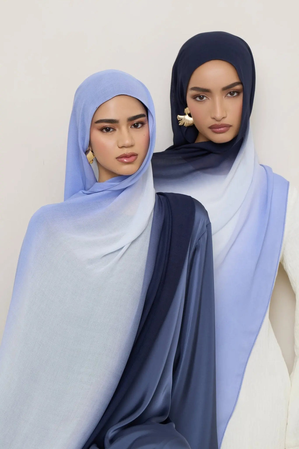 Two women wearing light blue hijabs against a white background
