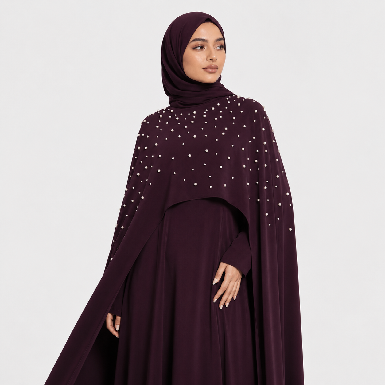 Woman wearing a dark purple dress with white embellishments on a light gray background
