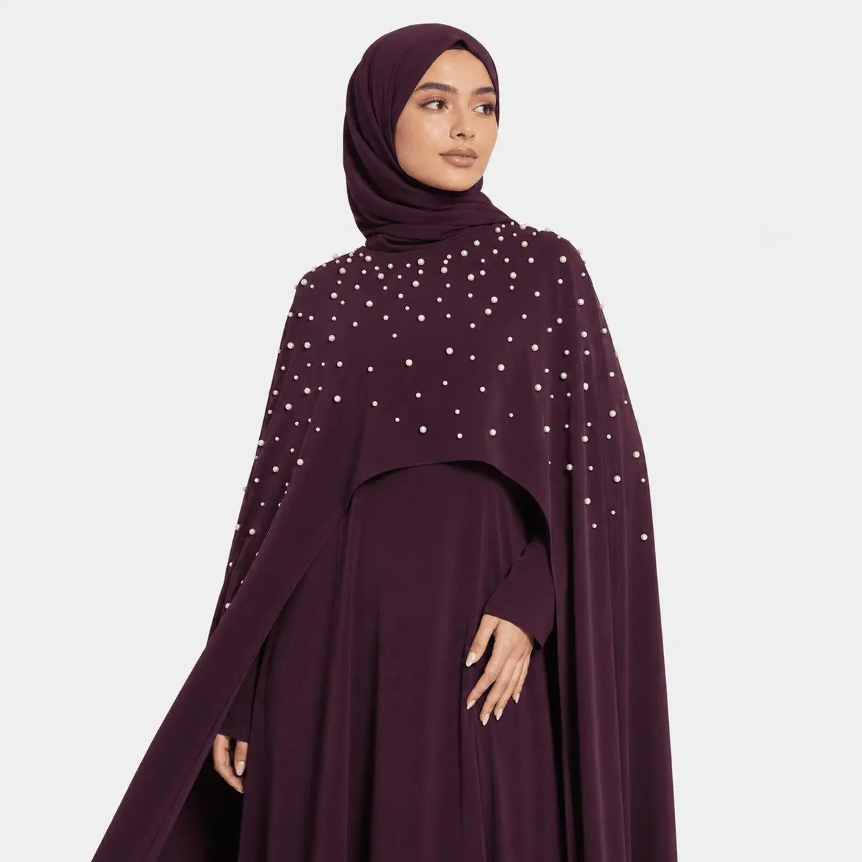 Woman wearing a dark purple dress with white embellishments on a light gray background