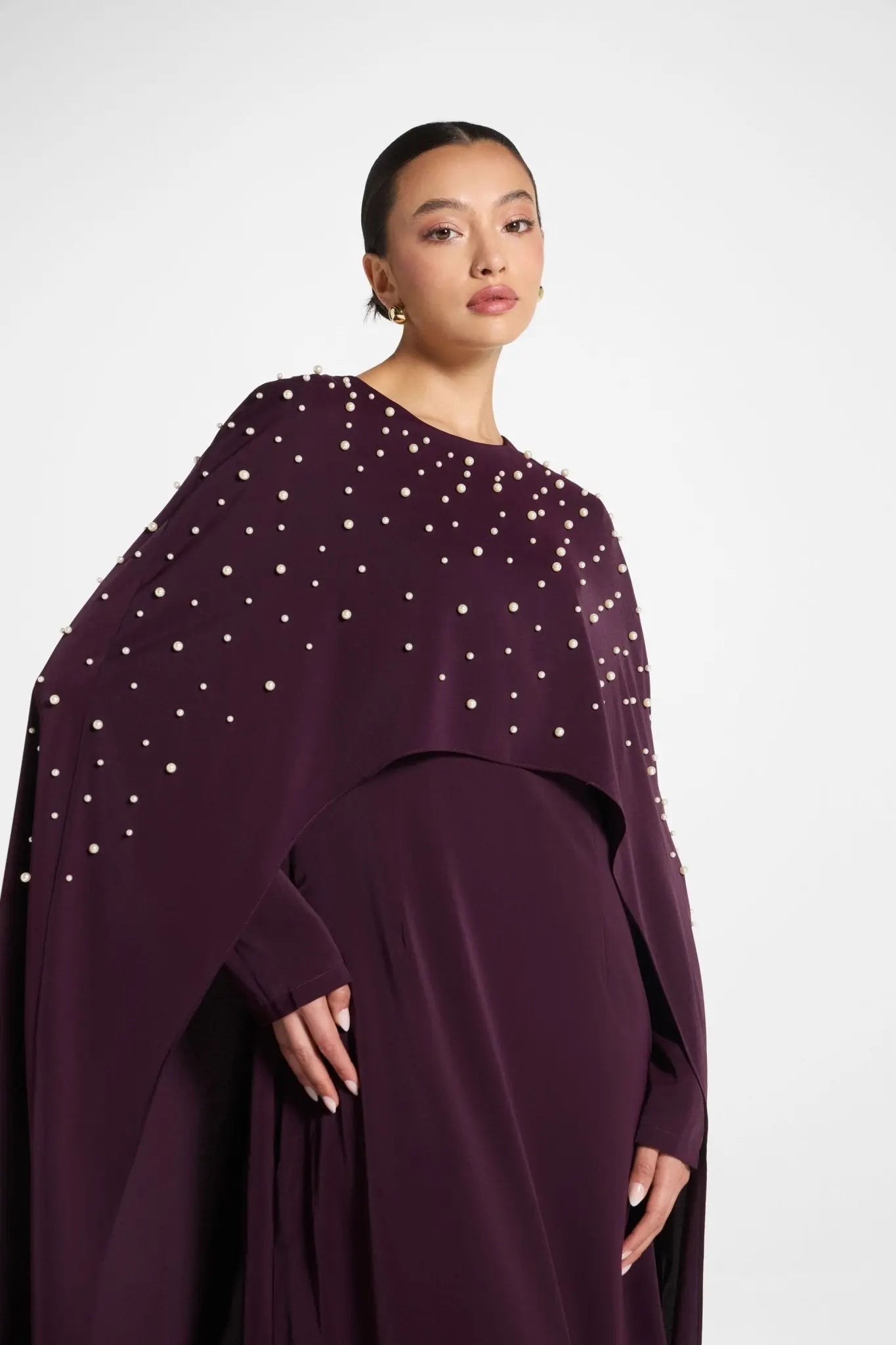 Woman wearing a dark purple dress with silver embellishments on a white background