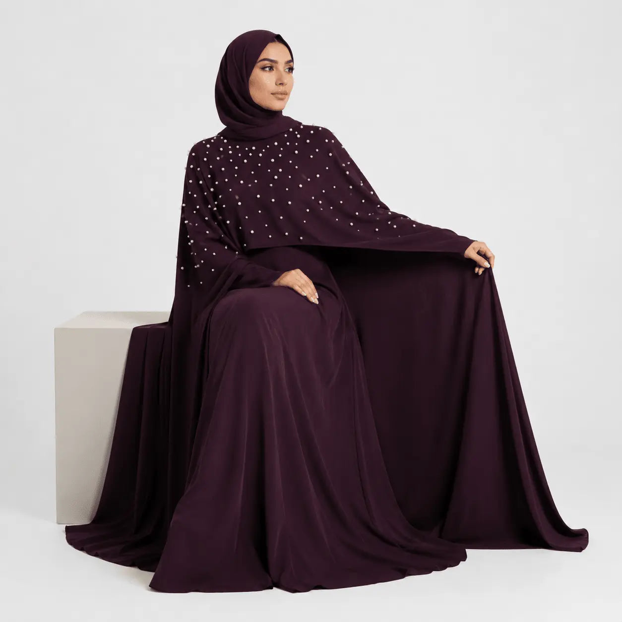 Woman wearing a dark purple abaya with star patterns on a white background