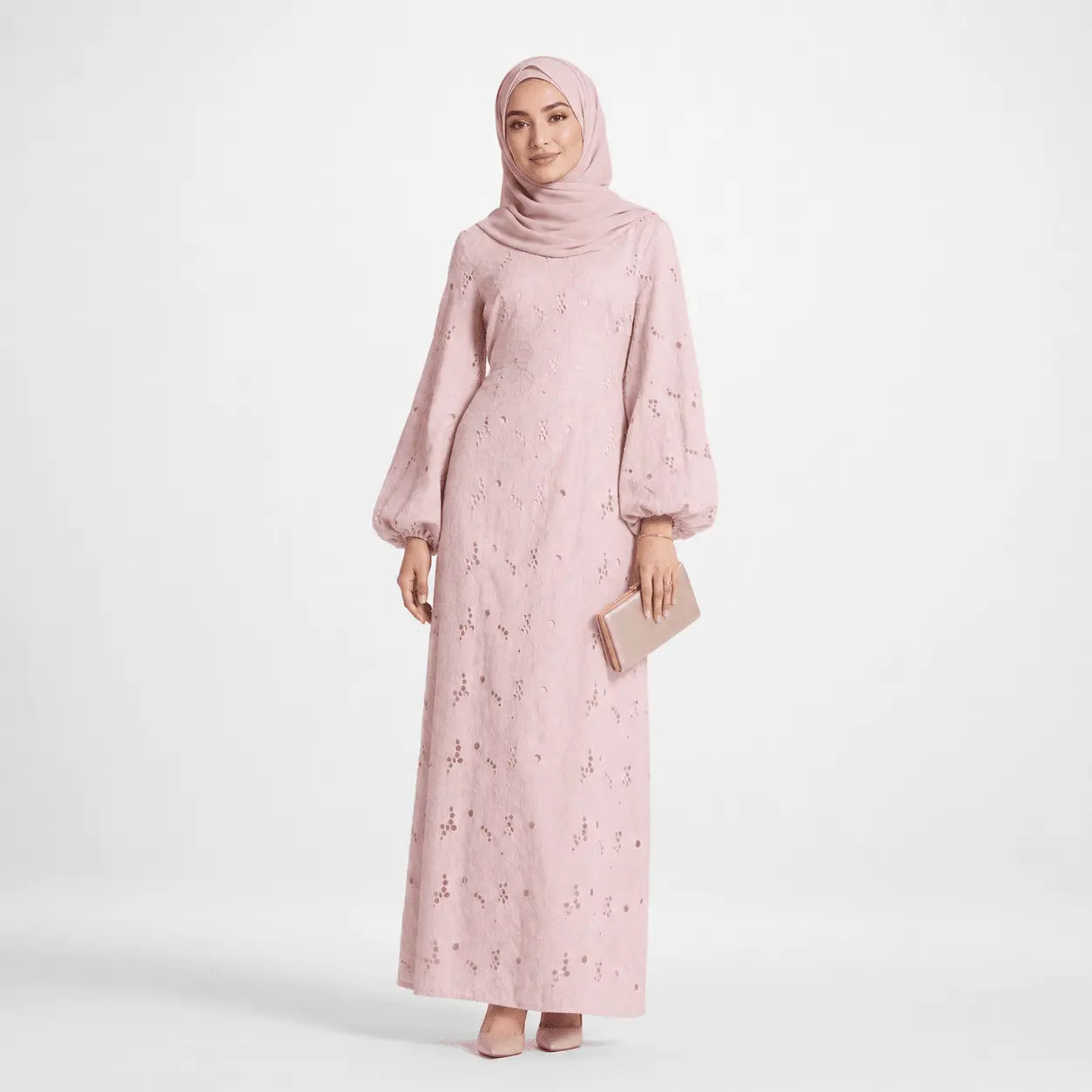 Woman in blush pink modest dress with puff sleeves, matching hijab, and clutch, elegant Muslim fashion
