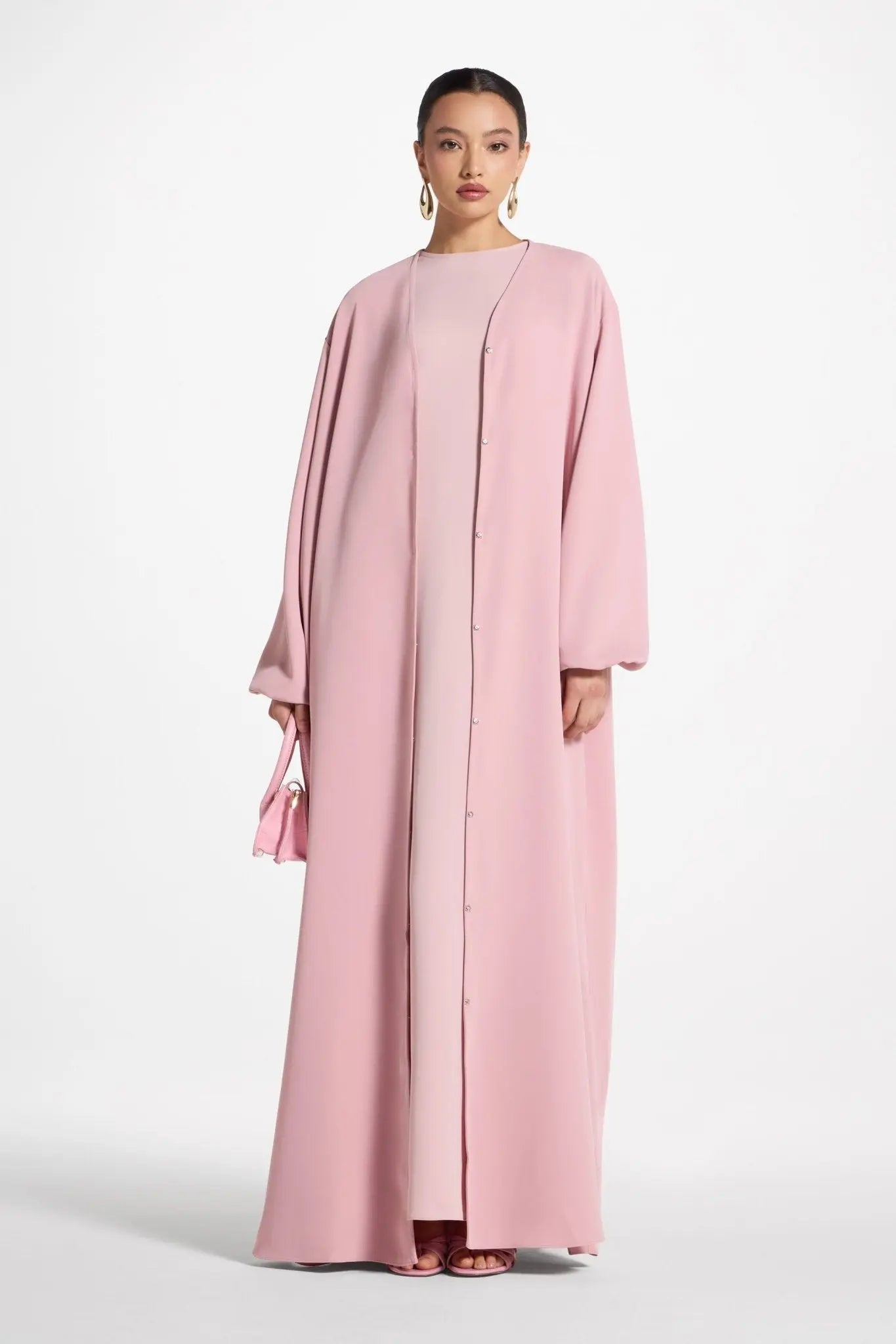 Woman wearing a pink abaya on a white background