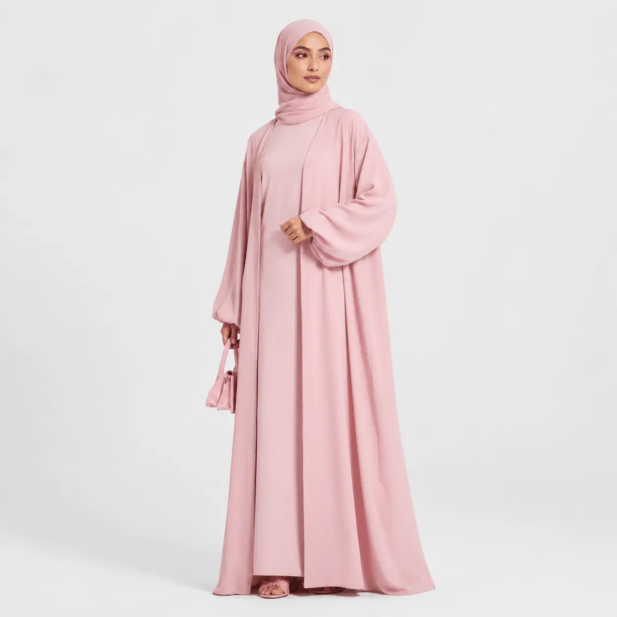 Woman wearing a pink abaya on a white background