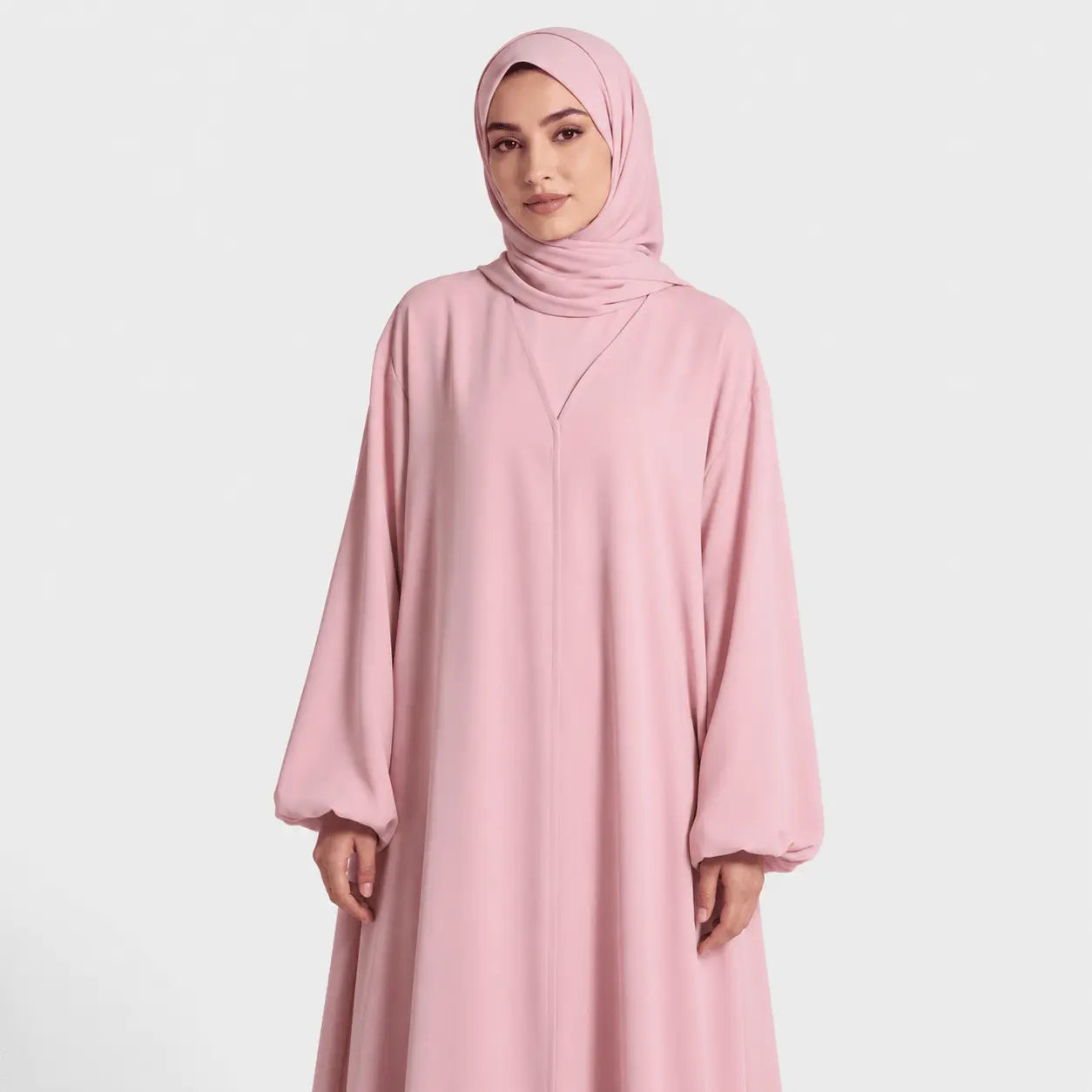 Woman wearing a pink abaya and hijab on a white background