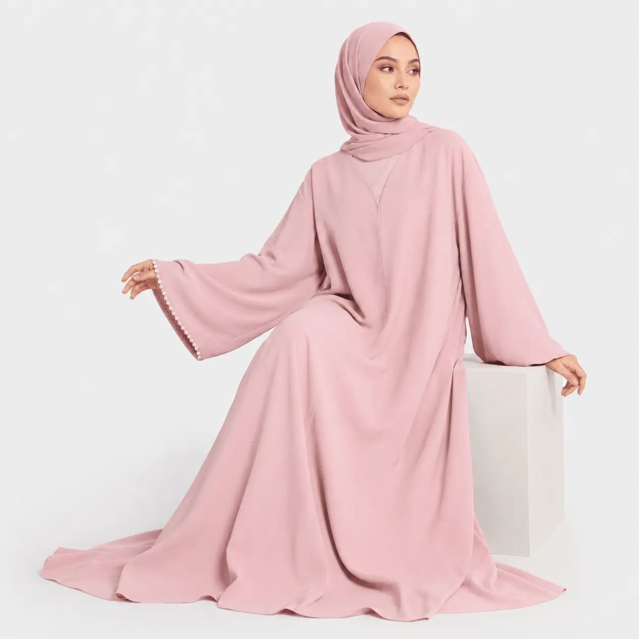 Woman wearing a pink abaya on a white background