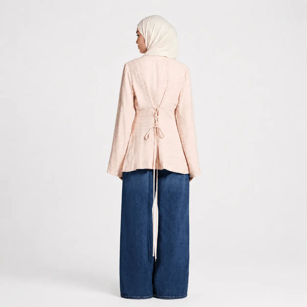 Person wearing a light pink top and blue jeans on a white background