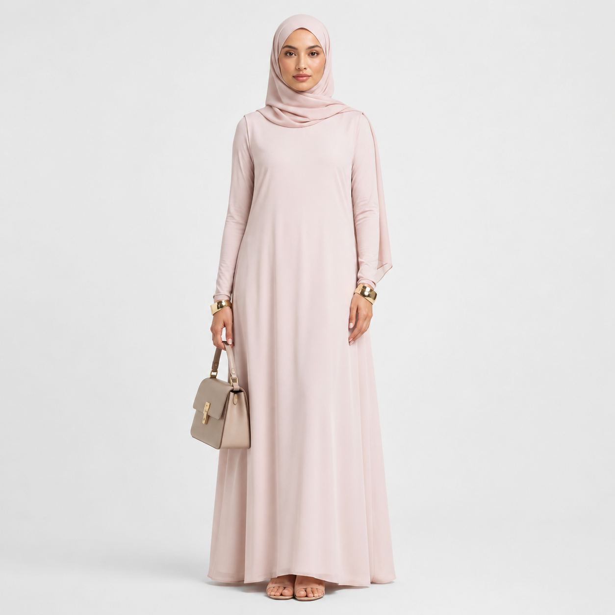 Woman wearing a long light pink dress and hijab on a white background