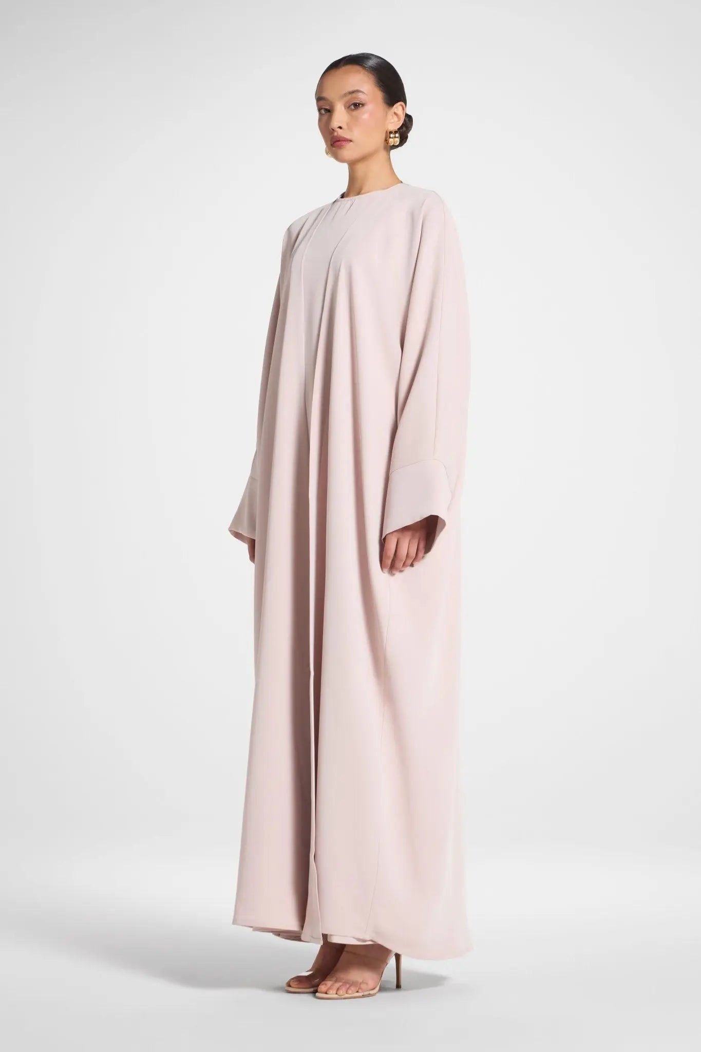 Woman wearing a long, light pink dress against a white background