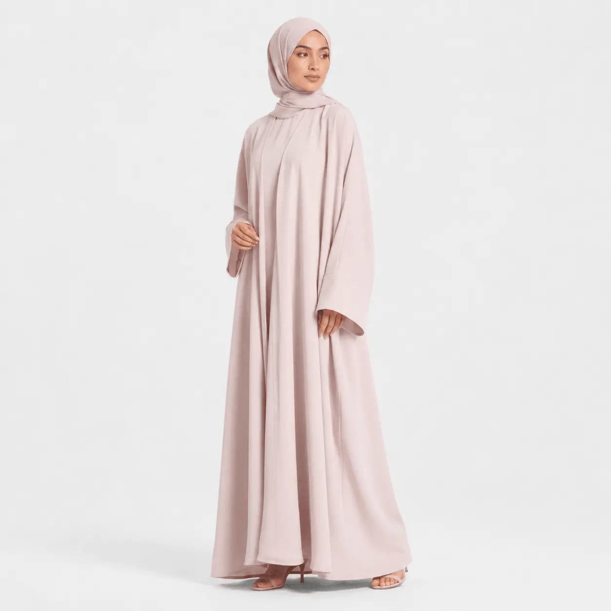 Woman wearing a light pink abaya on a white background