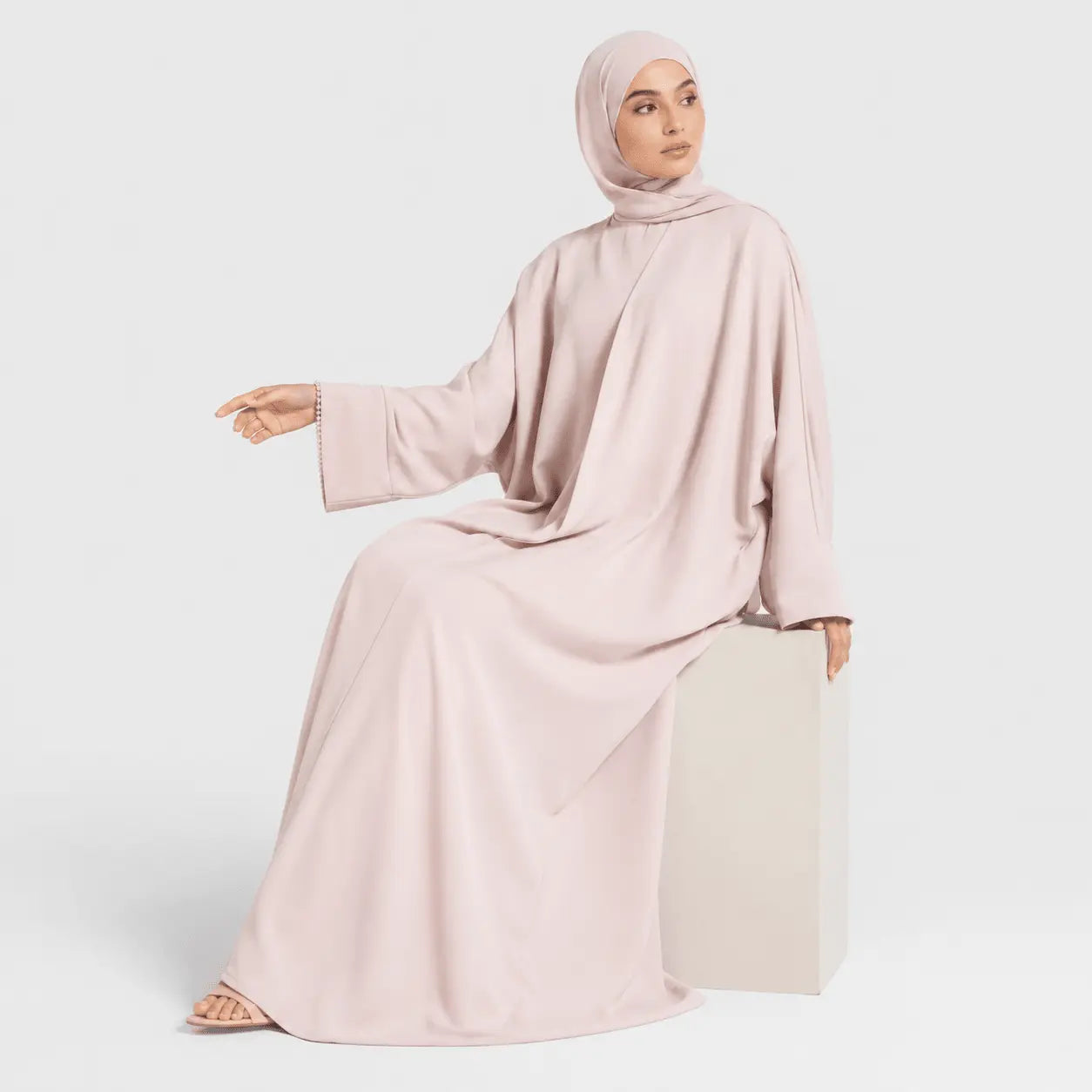 Woman wearing a light pink abaya on a white background