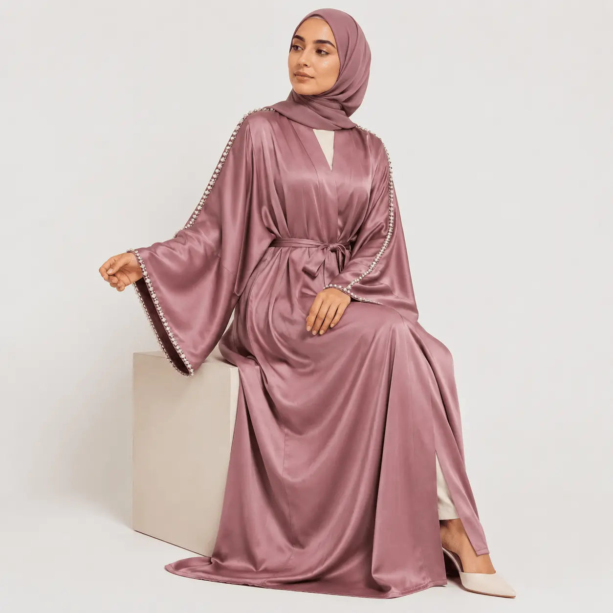 Woman wearing a mauve abaya with embellishments on a white background