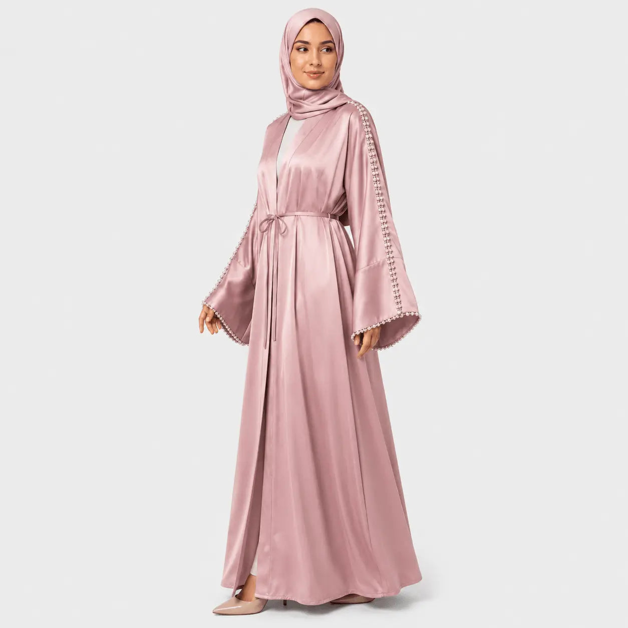 Woman wearing a pink abaya with lace sleeves on a light gray background