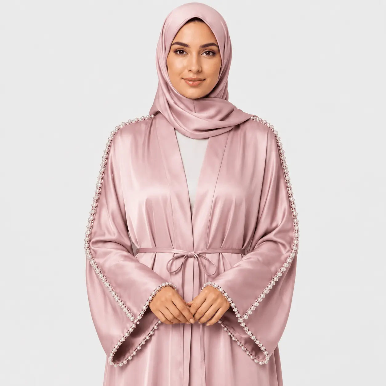 Woman wearing a pink abaya with decorative trim on a light gray background