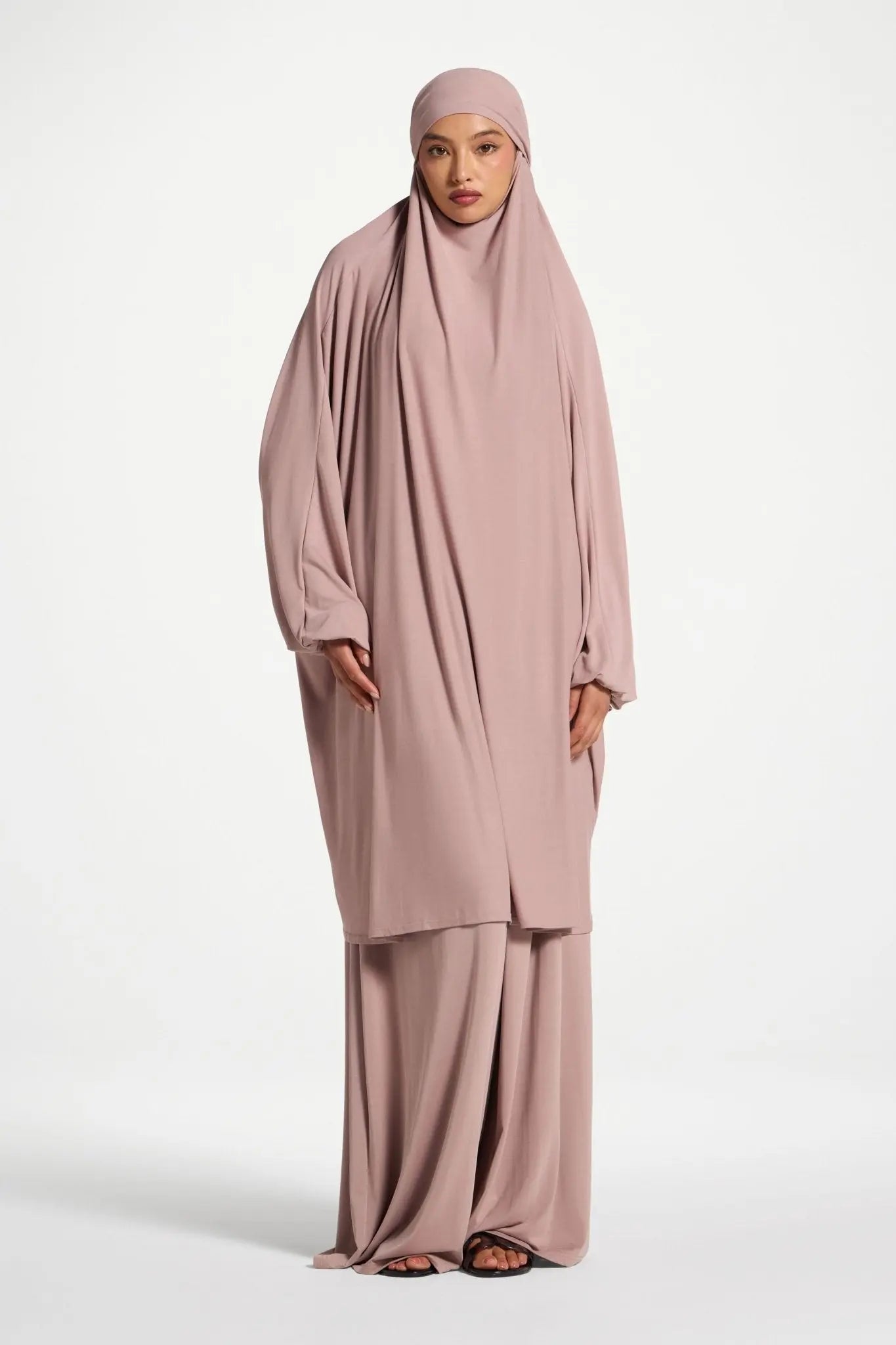 Woman wearing a pink abaya on a white background