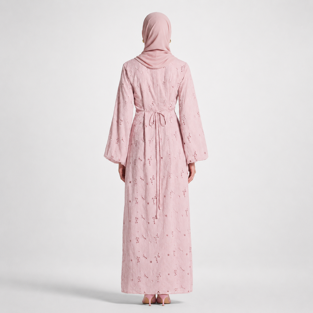 Person wearing a pink abaya with floral patterns on a white background