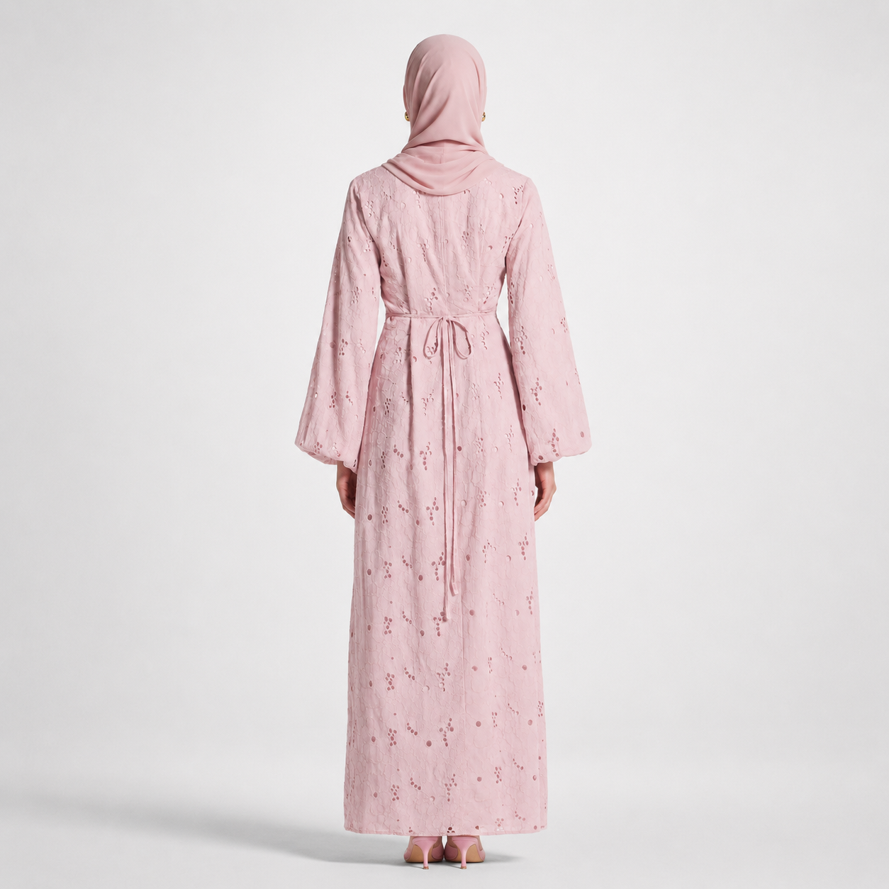 Person wearing a pink abaya with floral patterns on a white background