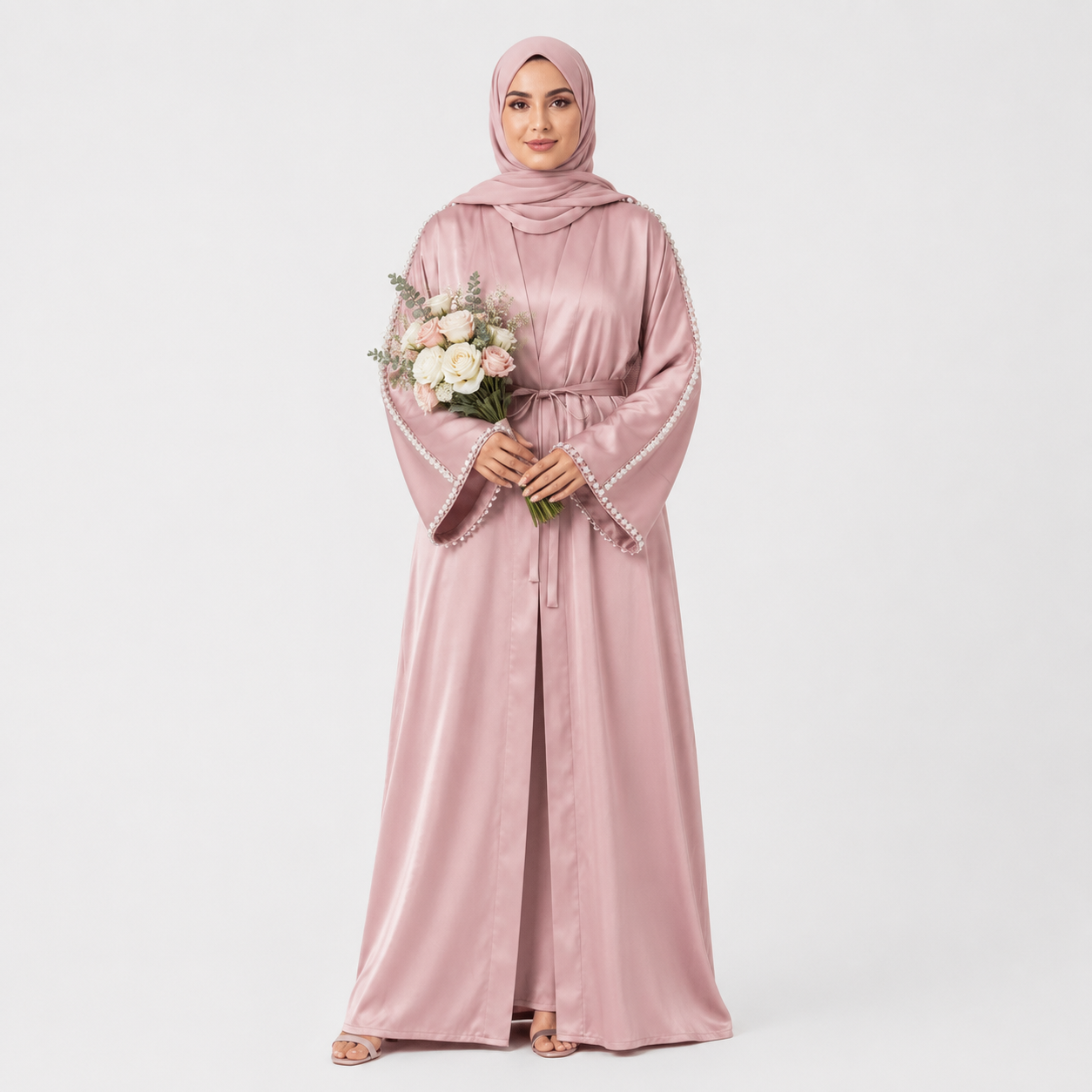 Woman wearing a pink abaya holding flowers on a white background