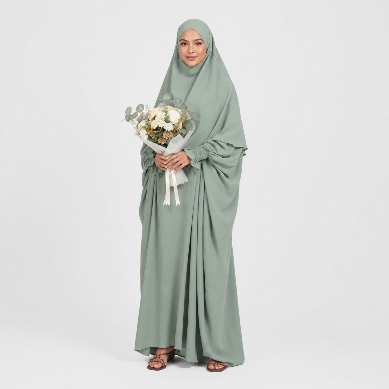 Woman wearing a long green dress holding flowers on a white background