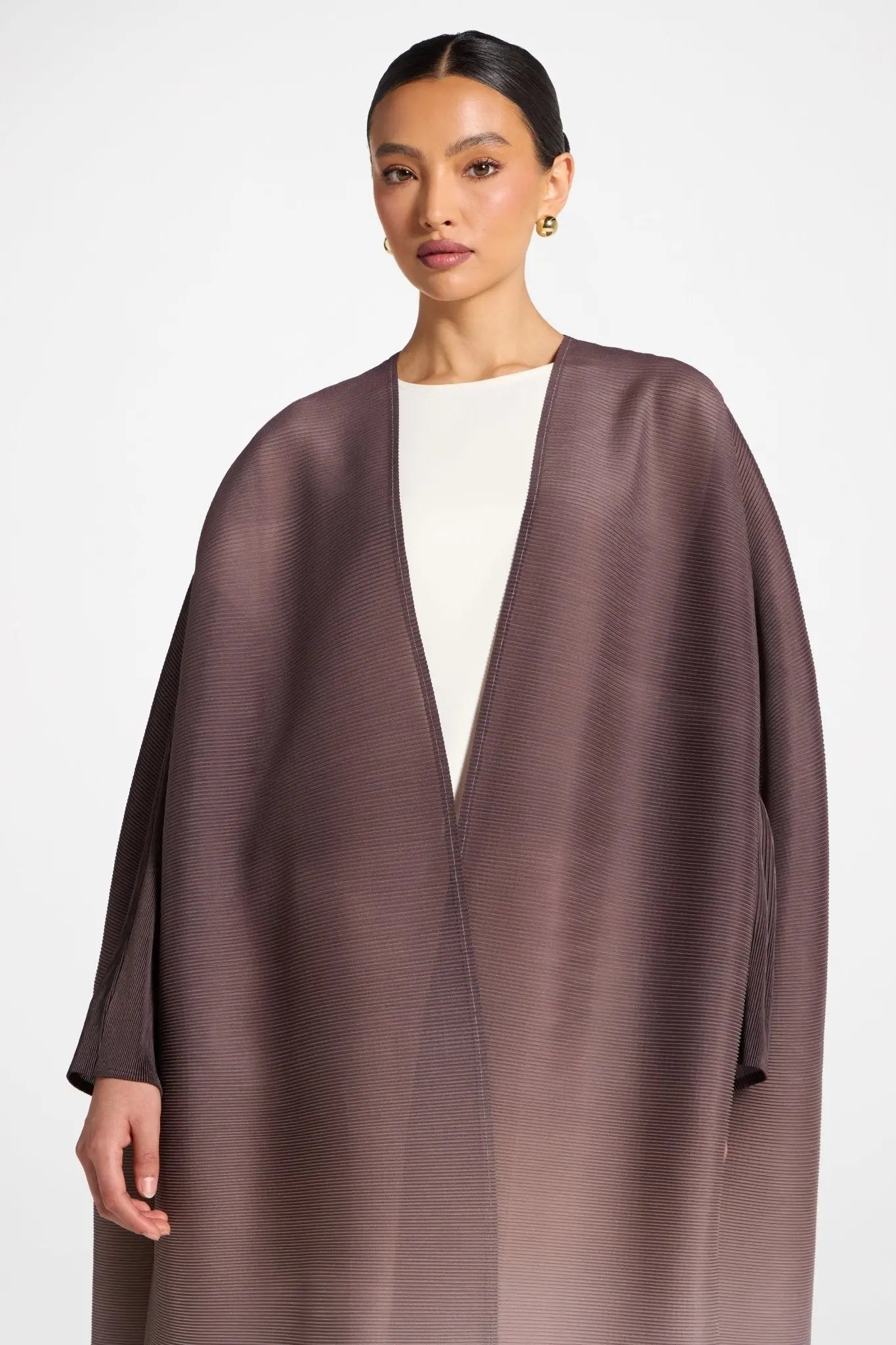 Woman wearing a brown cape over a white top on a white background