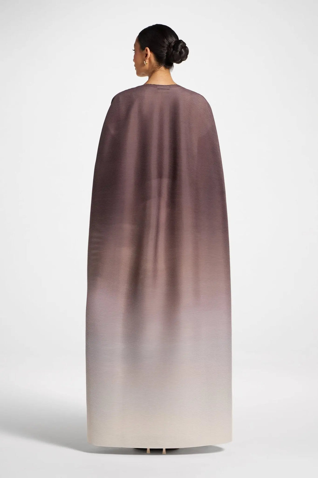 Woman wearing a long, gradient dress with a white background