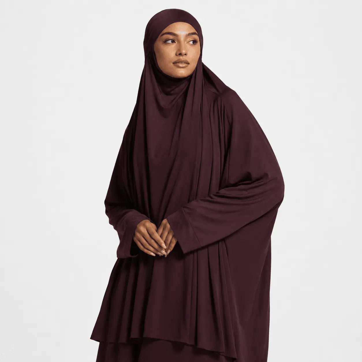 Woman wearing a dark brown hijab and dress on a white background