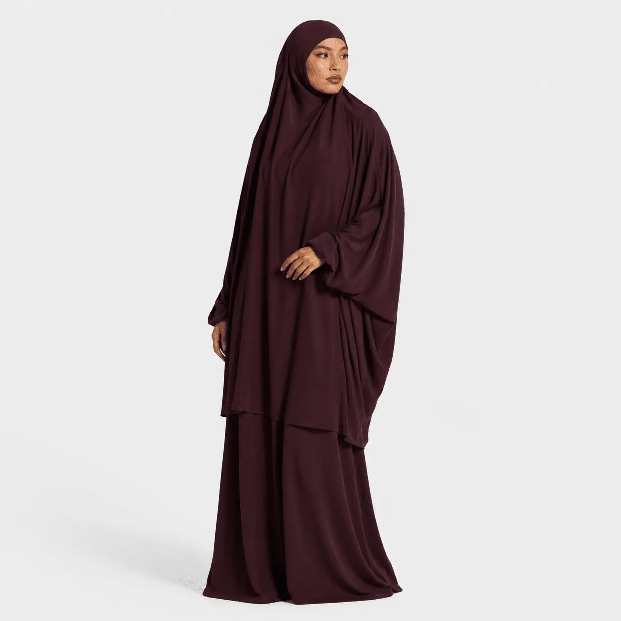 Woman wearing a dark brown abaya on a light gray background