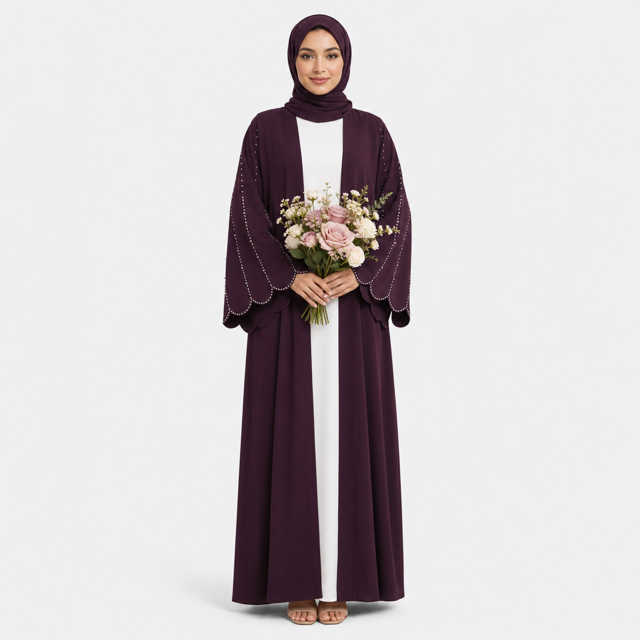 Woman wearing a long dark purple dress with a matching hijab, holding flowers on a light gray background