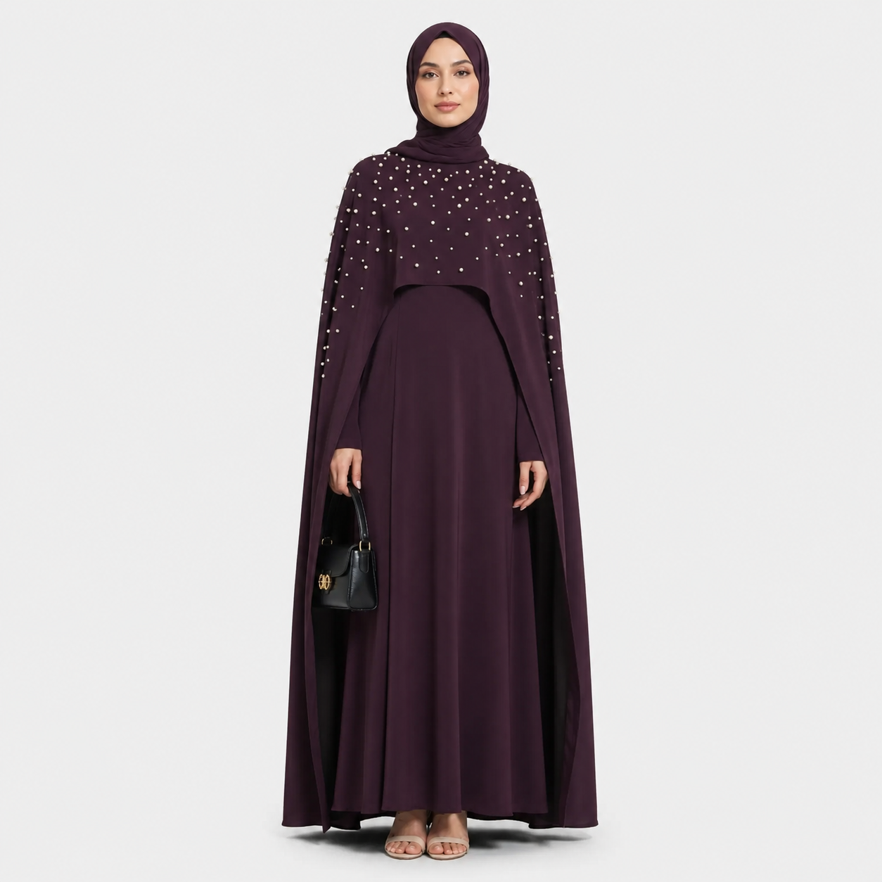 Woman wearing a dark purple abaya with embellishments on a white background