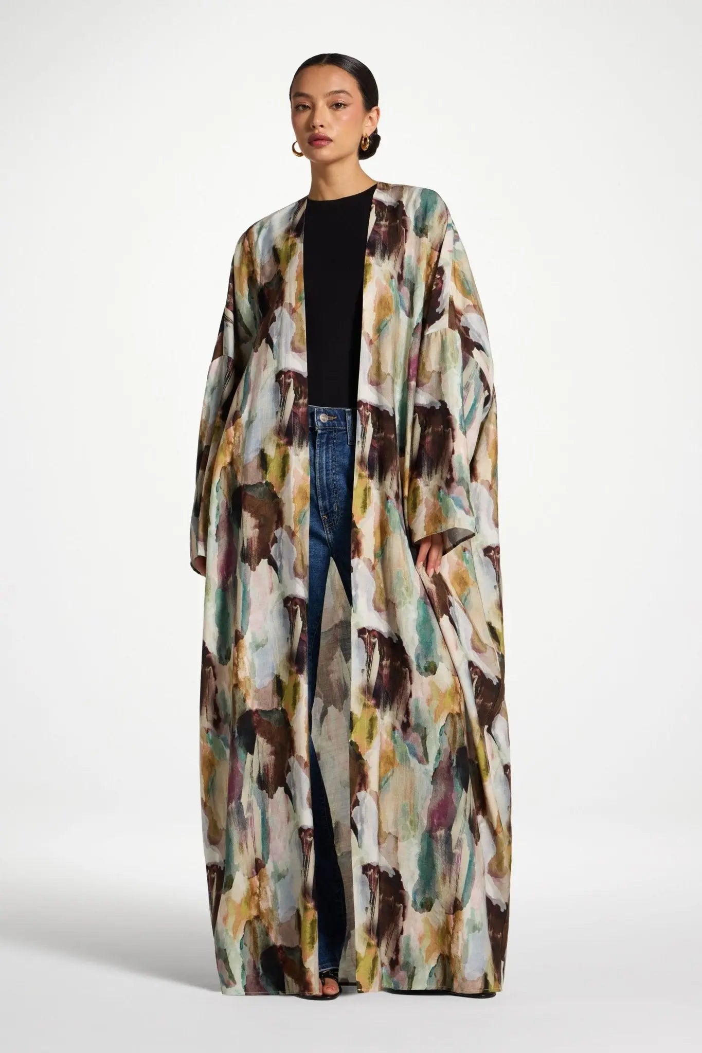 Woman wearing a long, patterned coat on a white background