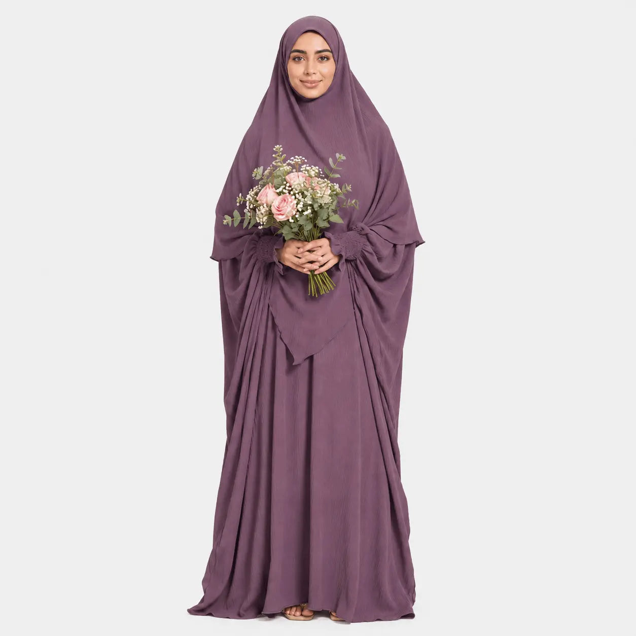 Woman wearing a purple abaya holding flowers on a white background