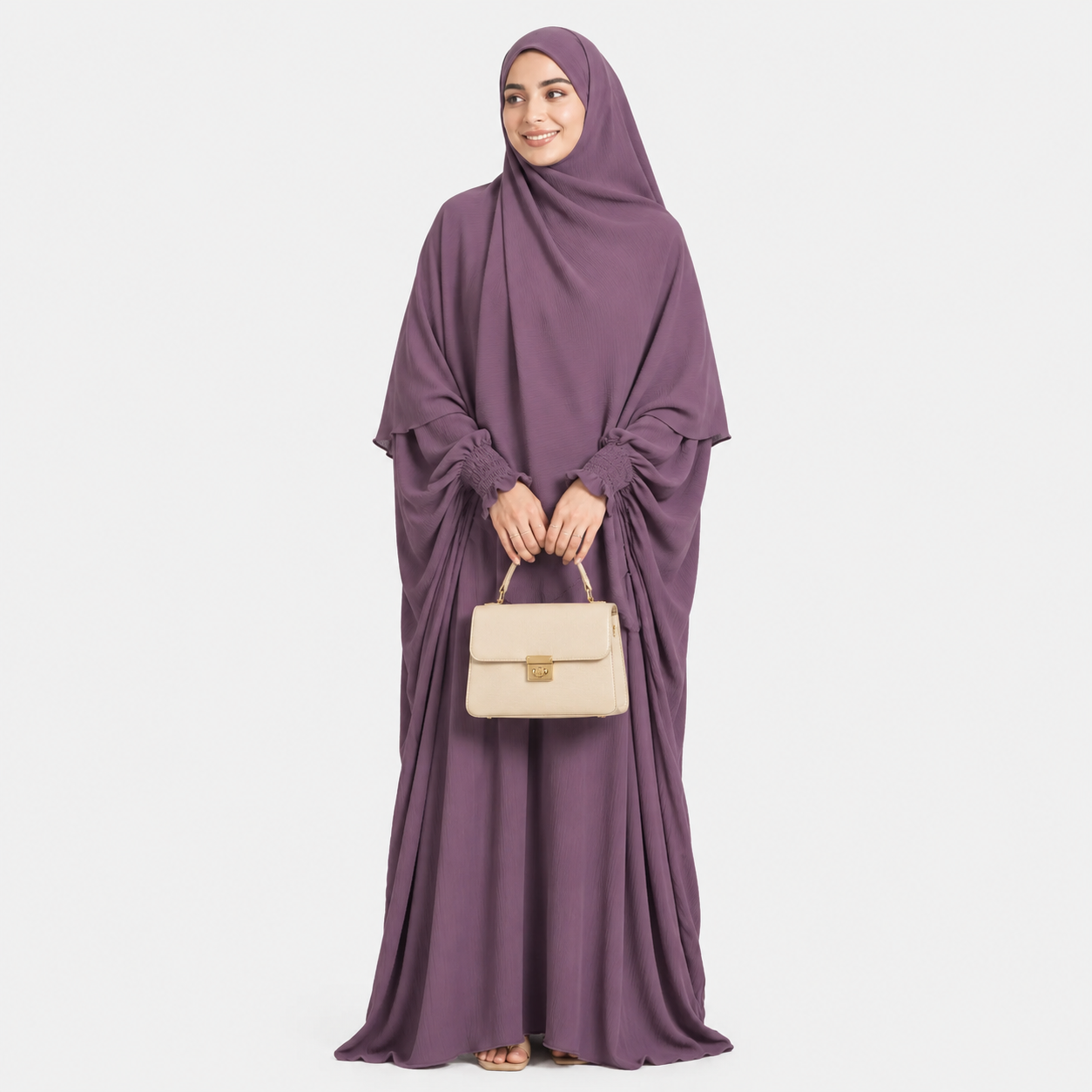 Woman wearing a long purple dress holding a beige handbag on a white background