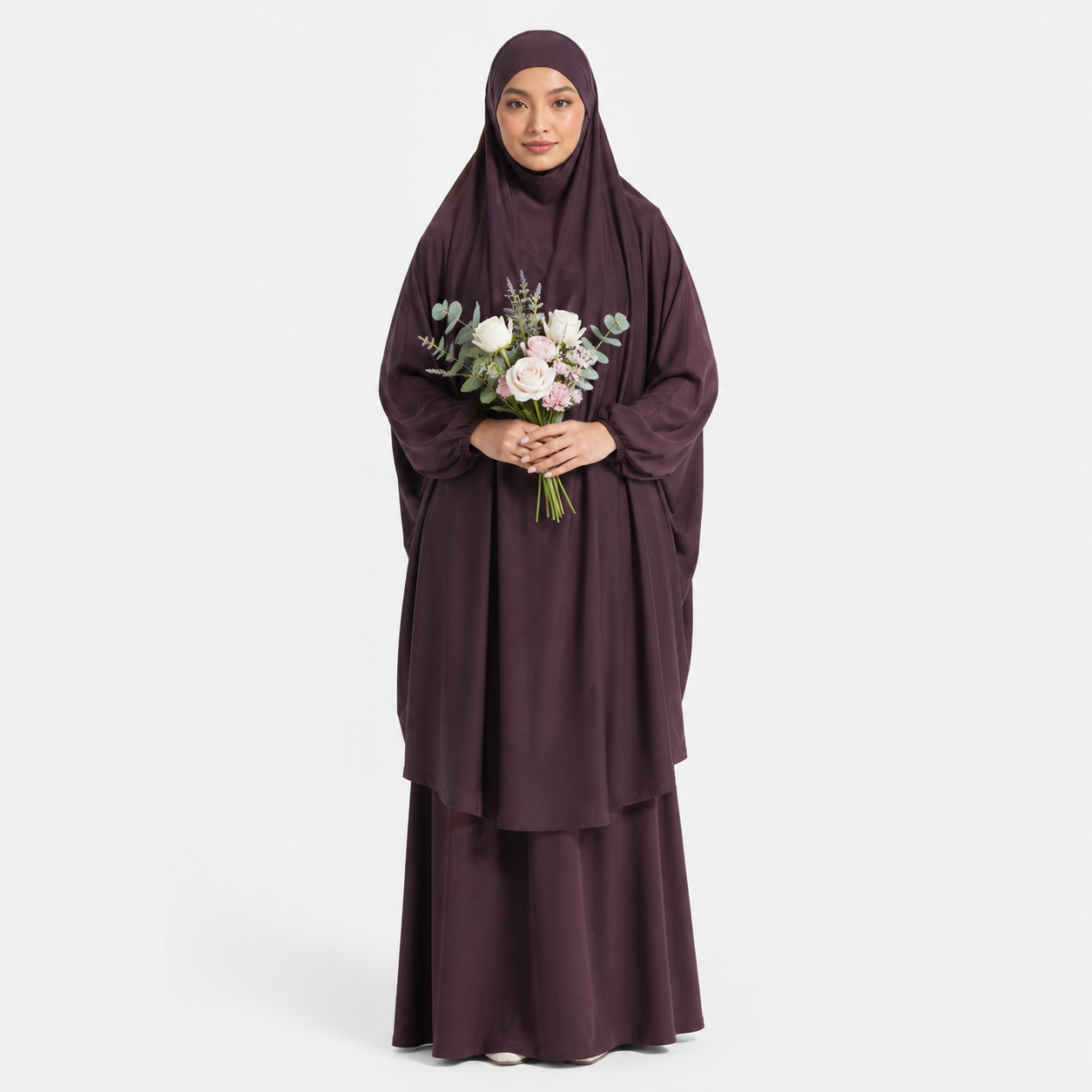 Woman wearing a dark purple abaya holding flowers on a white background