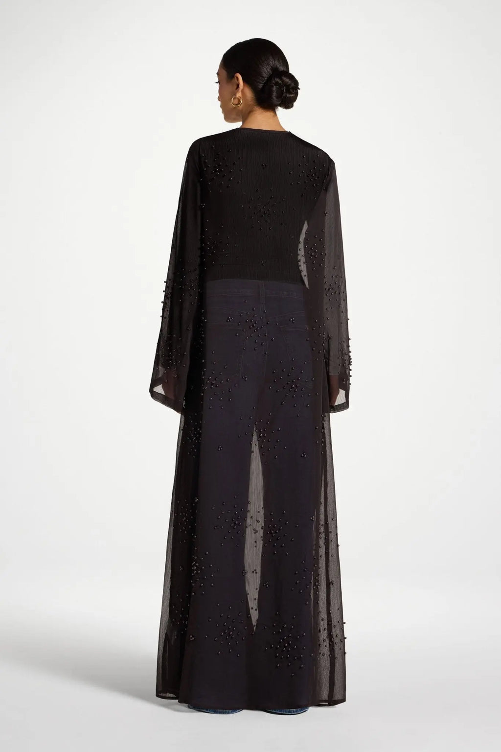 Woman wearing a black outfit with sheer sleeves on a white background