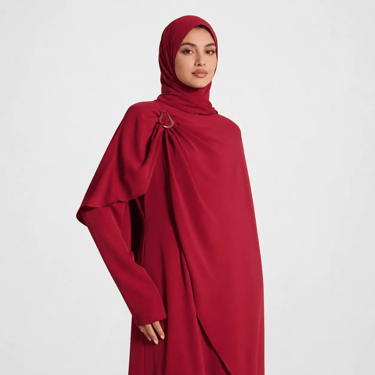 Woman wearing a red abaya with a plain background