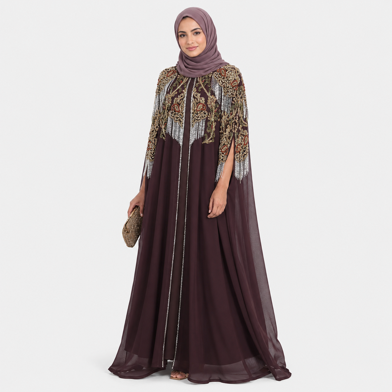 Woman wearing a long, dark brown dress with gold embroidery on a white background
