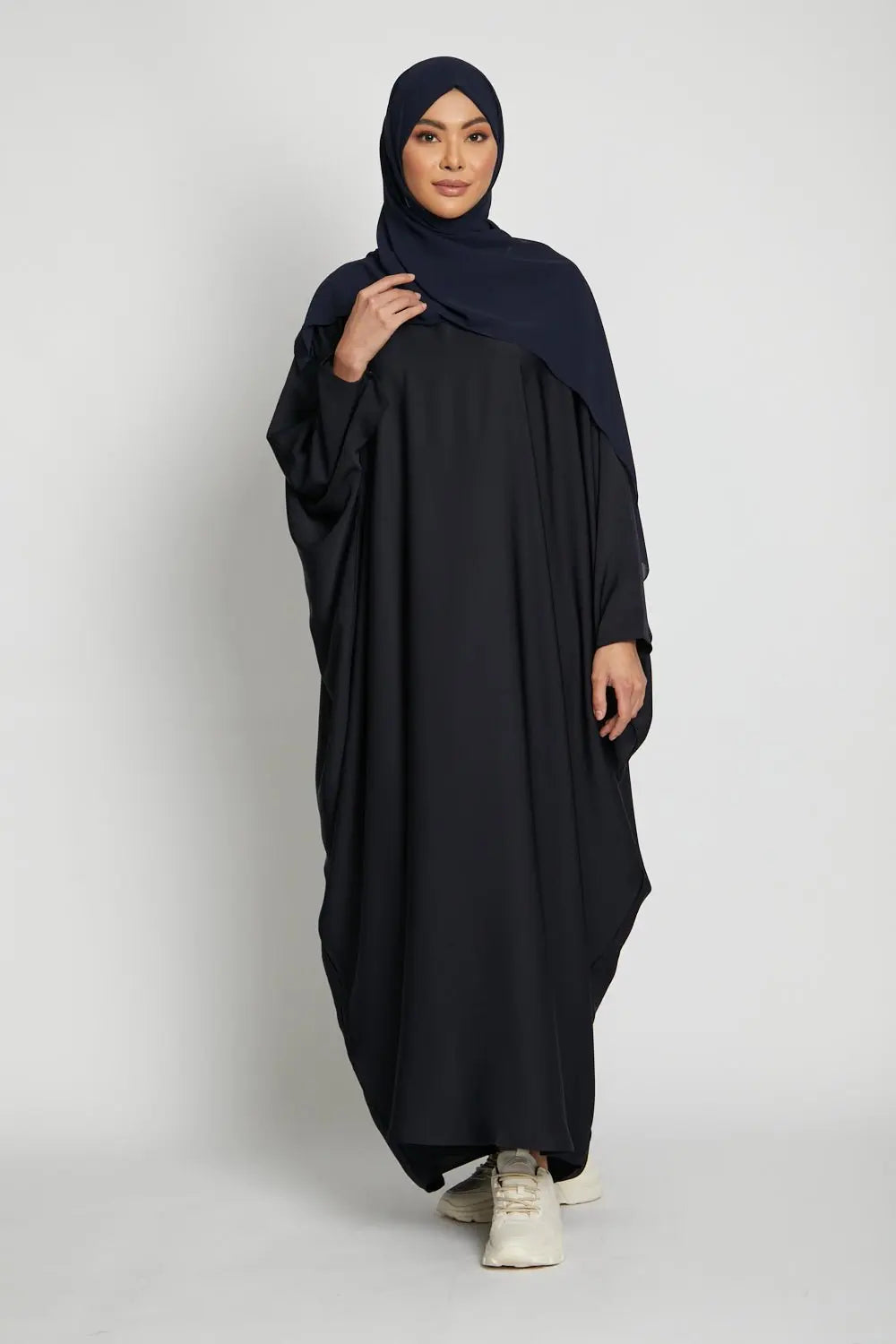 Woman wearing a black abaya and hijab on a white background